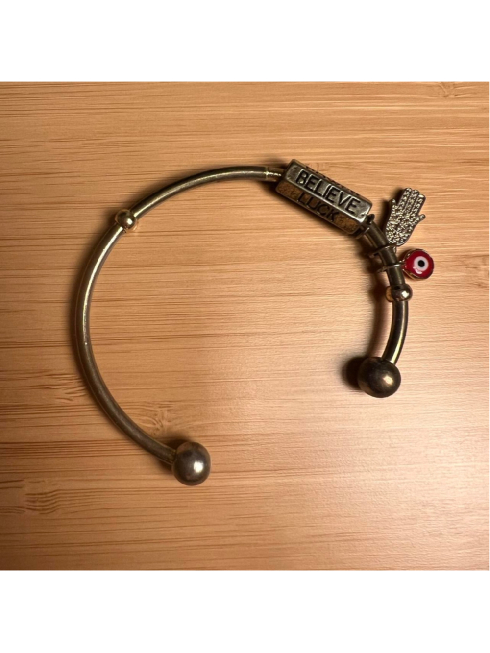 Gold bangle bracelet with hands and evil eye charms and rotating column reading